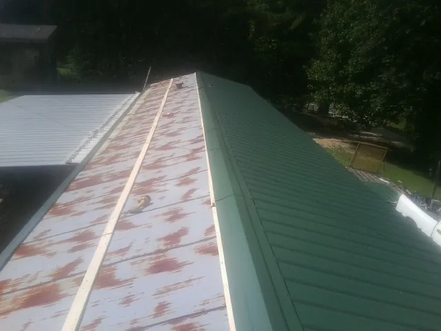 Old rusted panels beside newly installed green metal roofing — Wind Damage Roof Repair by Roofing Brothers in Hartville