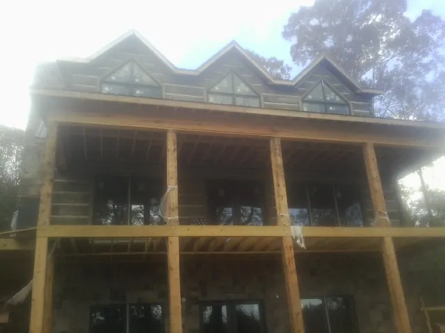 Dormers and porch framing on a large log home under construction — Roof Coating work by our crew in Hartville