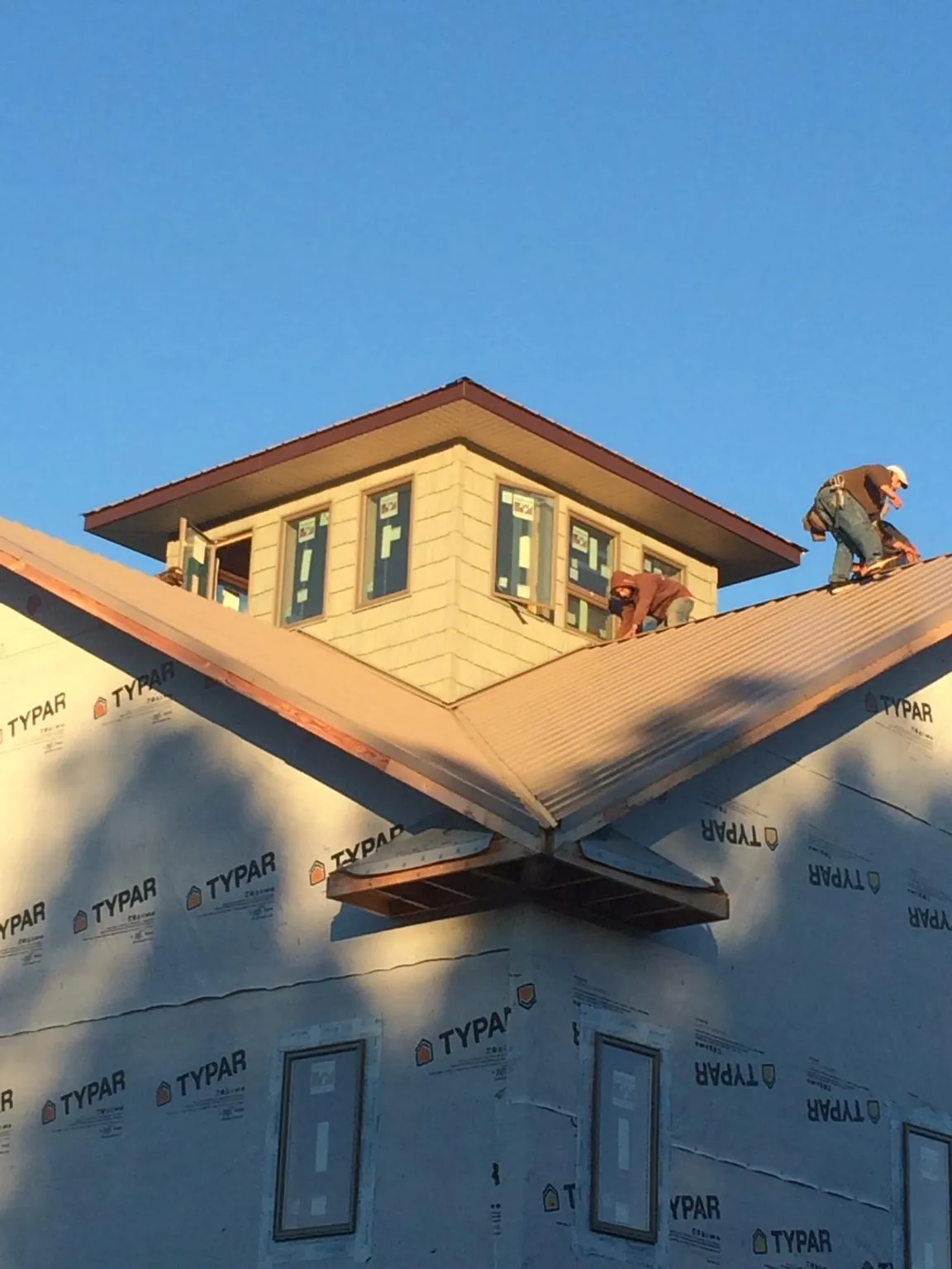 Roofers working around a rooftop cupola on a new metal roof at sunset — Roof Waterproofing in Hartville by Roofing Brothers